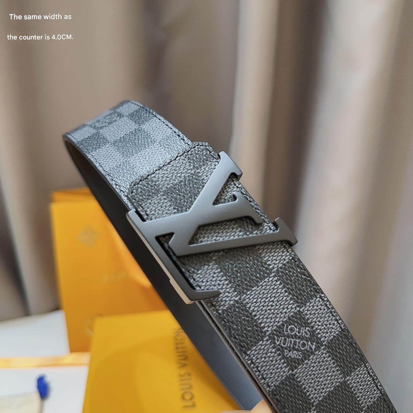 Gray checkered belt with a silver buckle on a blurred background