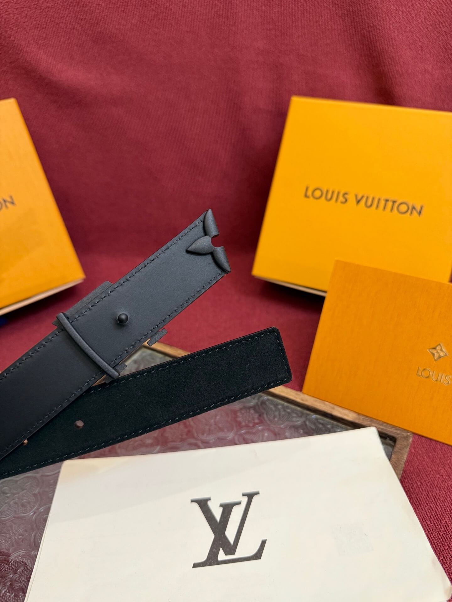 Louis Vuitton belt and boxes on a red surface