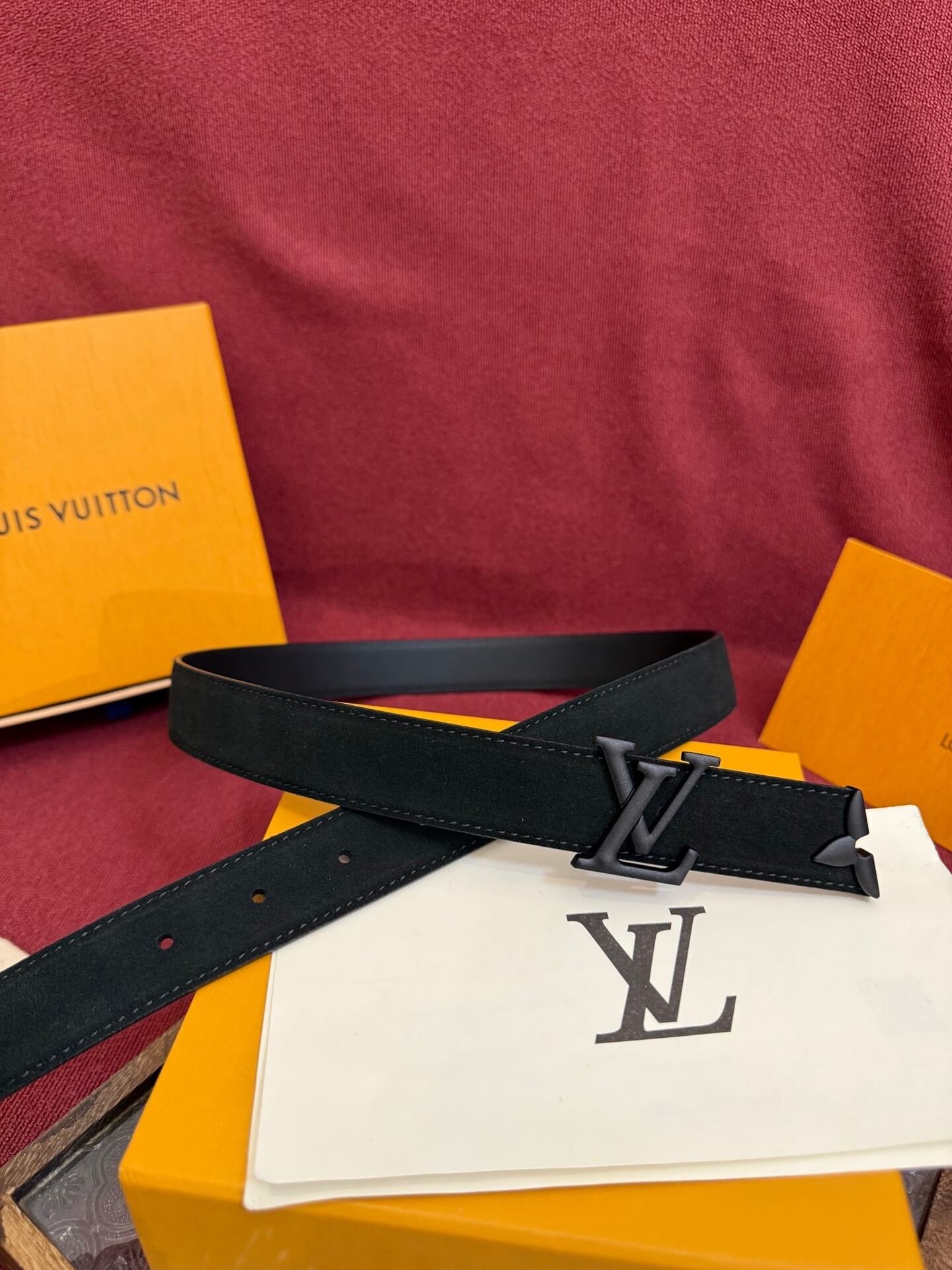 Black belt with a brand logo on a red surface with branded packaging.