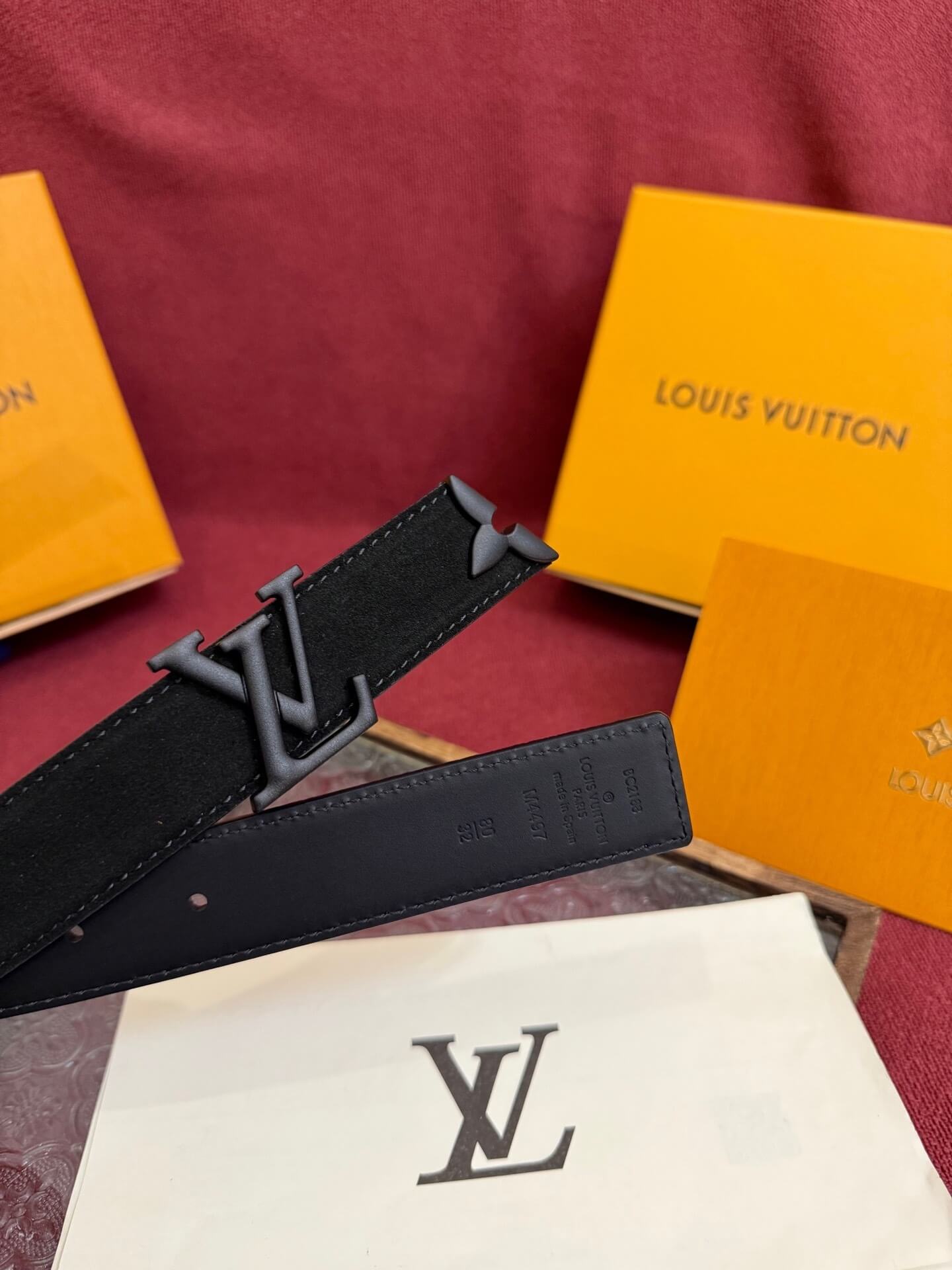 Louis Vuitton belt with packaging on a red surface