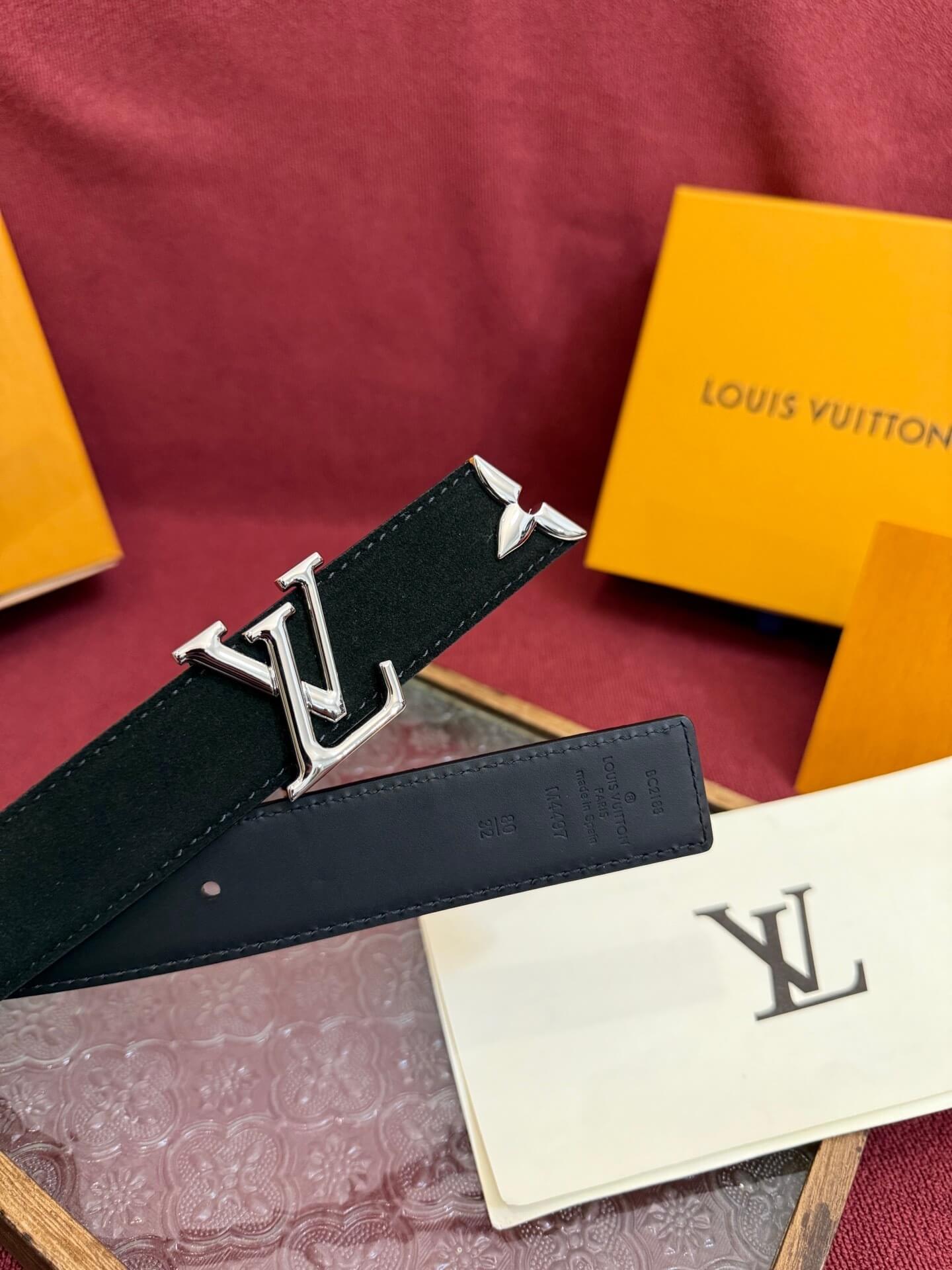 Louis Vuitton belt with logo and packaging on a red surface