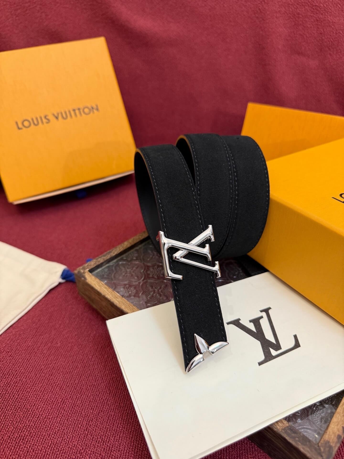 Black belt with silver buckle on a Louis Vuitton box and paper with logo.