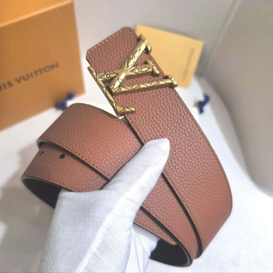 Brown leather belt with gold buckle held by a white gloved hand, with Louis Vuitton box in the background.