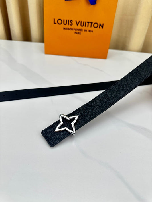 Black belt with star buckle on a white surface, with a Louis Vuitton bag in the background.