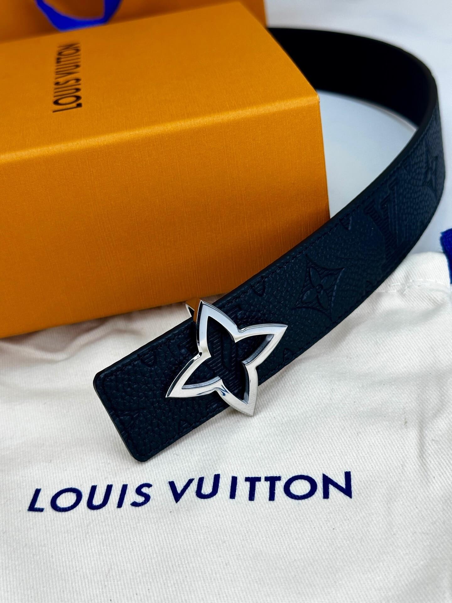 Black belt with silver buckle on a Louis Vuitton bag with an orange box in the background.