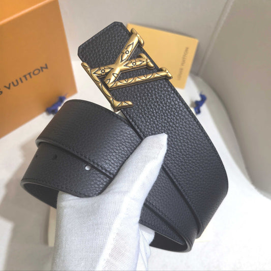 Black leather belt with gold buckle held by a gloved hand, with a Louis Vuitton box in the background.