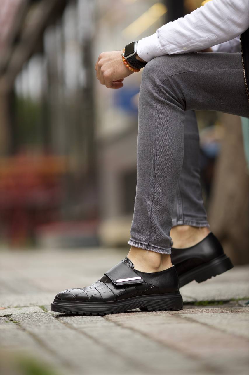 Luxurious Black Crocodile Patterned Leather Shoes – worn by a man seated in grey jeans, highlighting the laceless design and sophisticated crocodile pattern.
