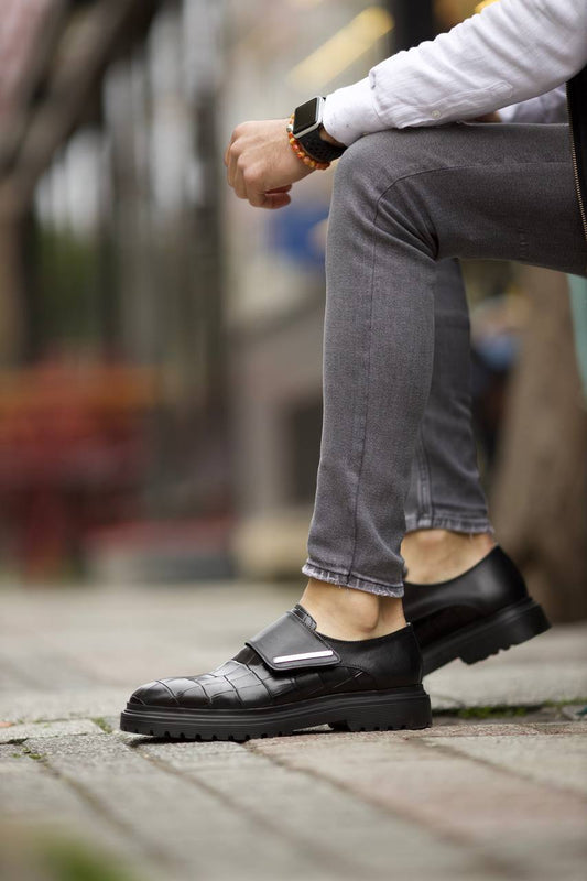 Luxurious Black Crocodile Patterned Leather Shoes – worn by a man seated in grey jeans, highlighting the laceless design and sophisticated crocodile pattern.