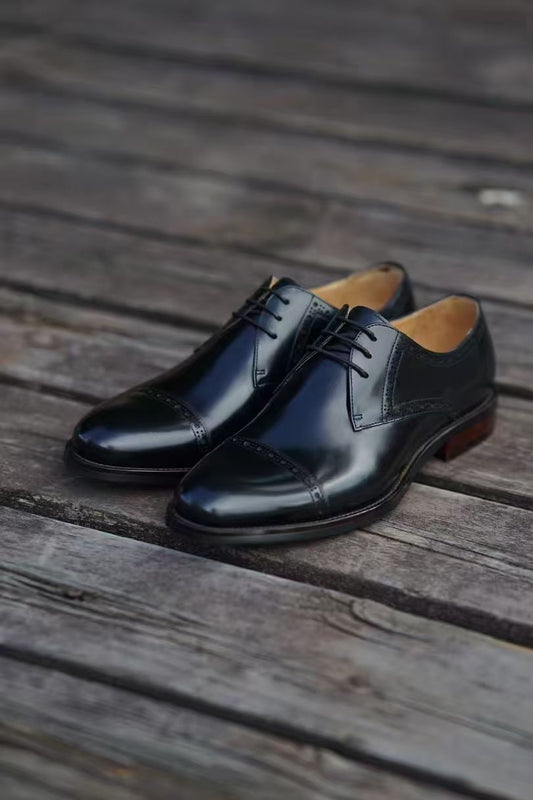 Pair of black dress shoes on a wooden surface