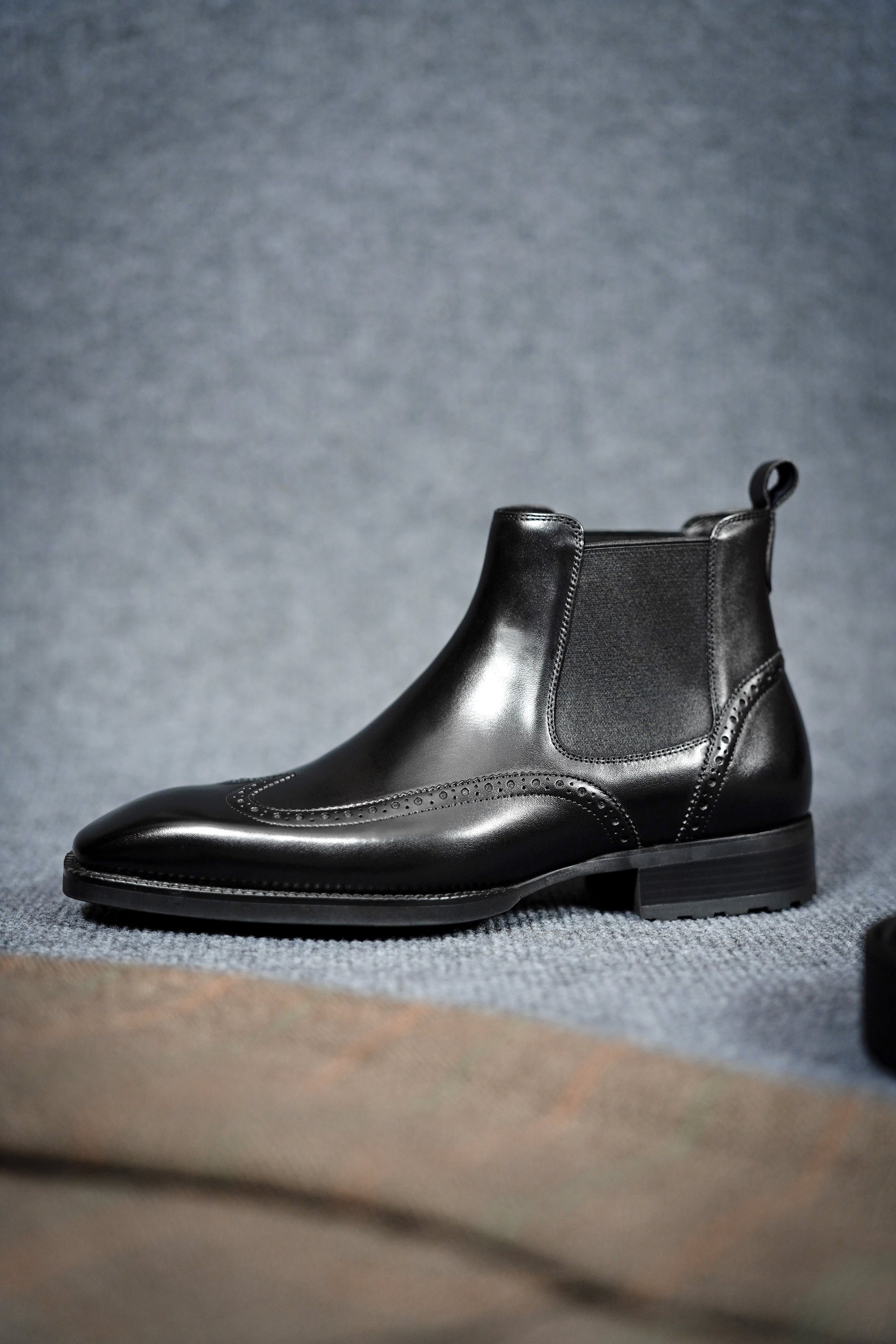 Modern Black Brogue Chelsea Boots for Sophisticated Style – a side view of a single boot, highlighting the intricate brogue detailing and polished leather finish.