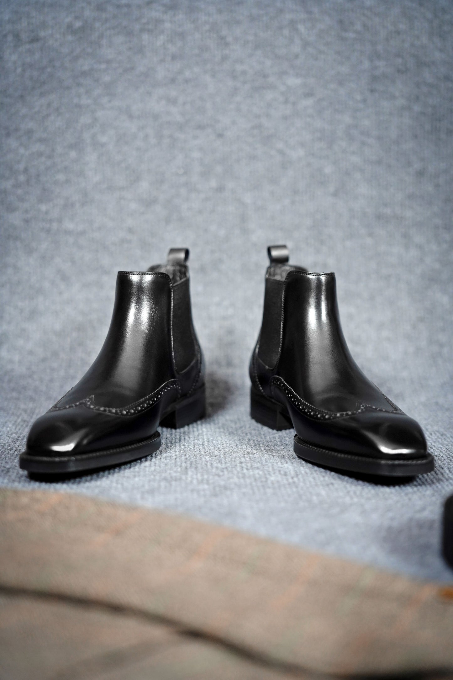 Modern Black Brogue Chelsea Boots for Sophisticated Style – a straight-on shot of the pair of black leather boots, focusing on the symmetrical wingtip brogue pattern.