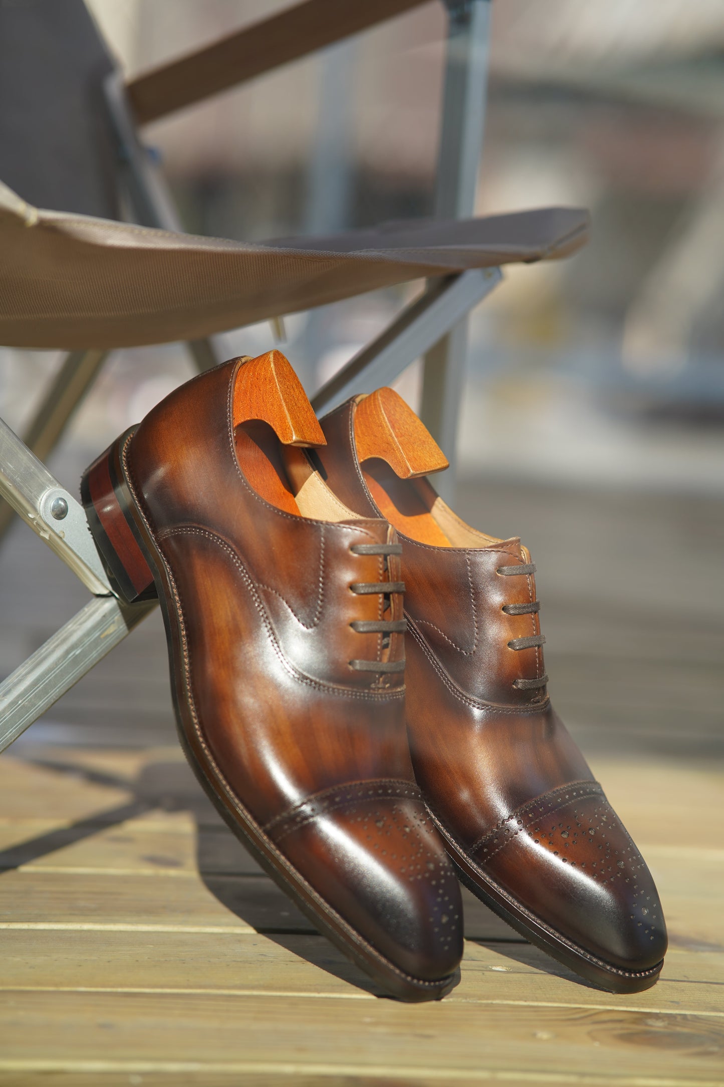 Close-up of men's brown leather Oxford shoes with intricate brogueing and a cap toe.