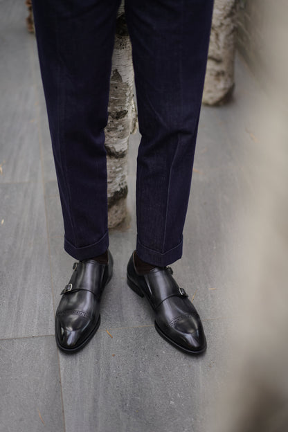 Polished Black Double Monk Strap Leather Shoes – worn by a man in cuffed dark blue trousers, showcasing their sleek appearance and modern formality.