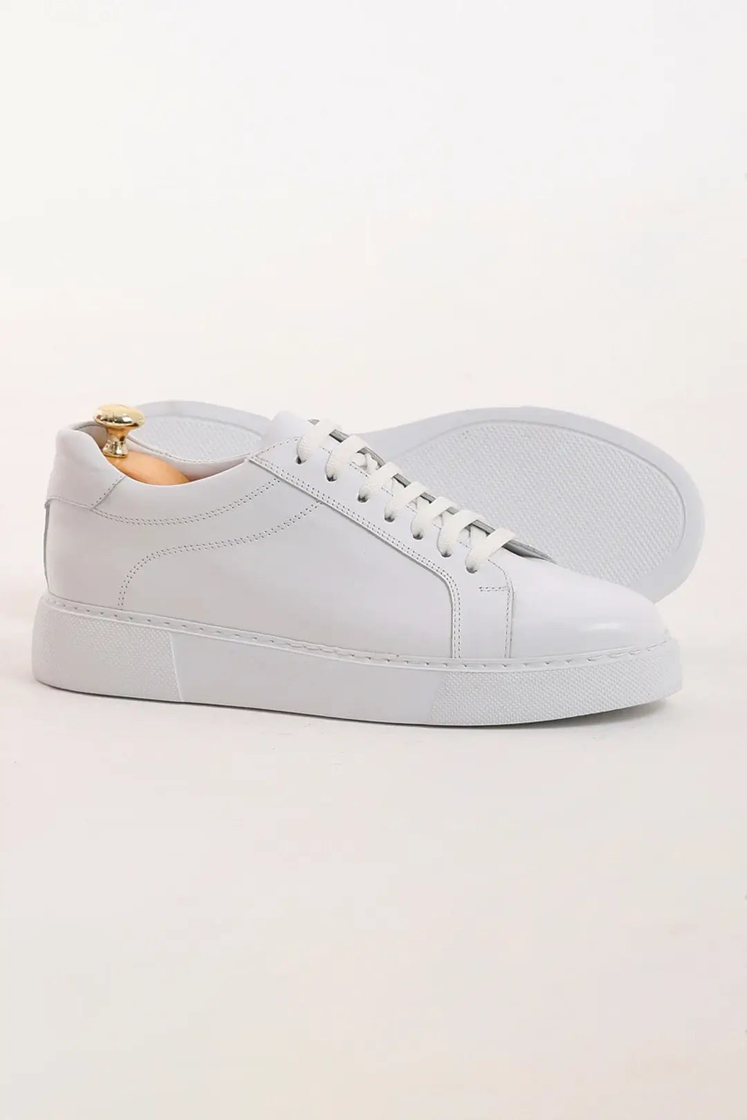 Pristine Luxe White Leather Sneakers - Luxury Comfort for Every Occasion – side view of one shoe with the other in the background, highlighting the durable rubber sole and a minimalist design.