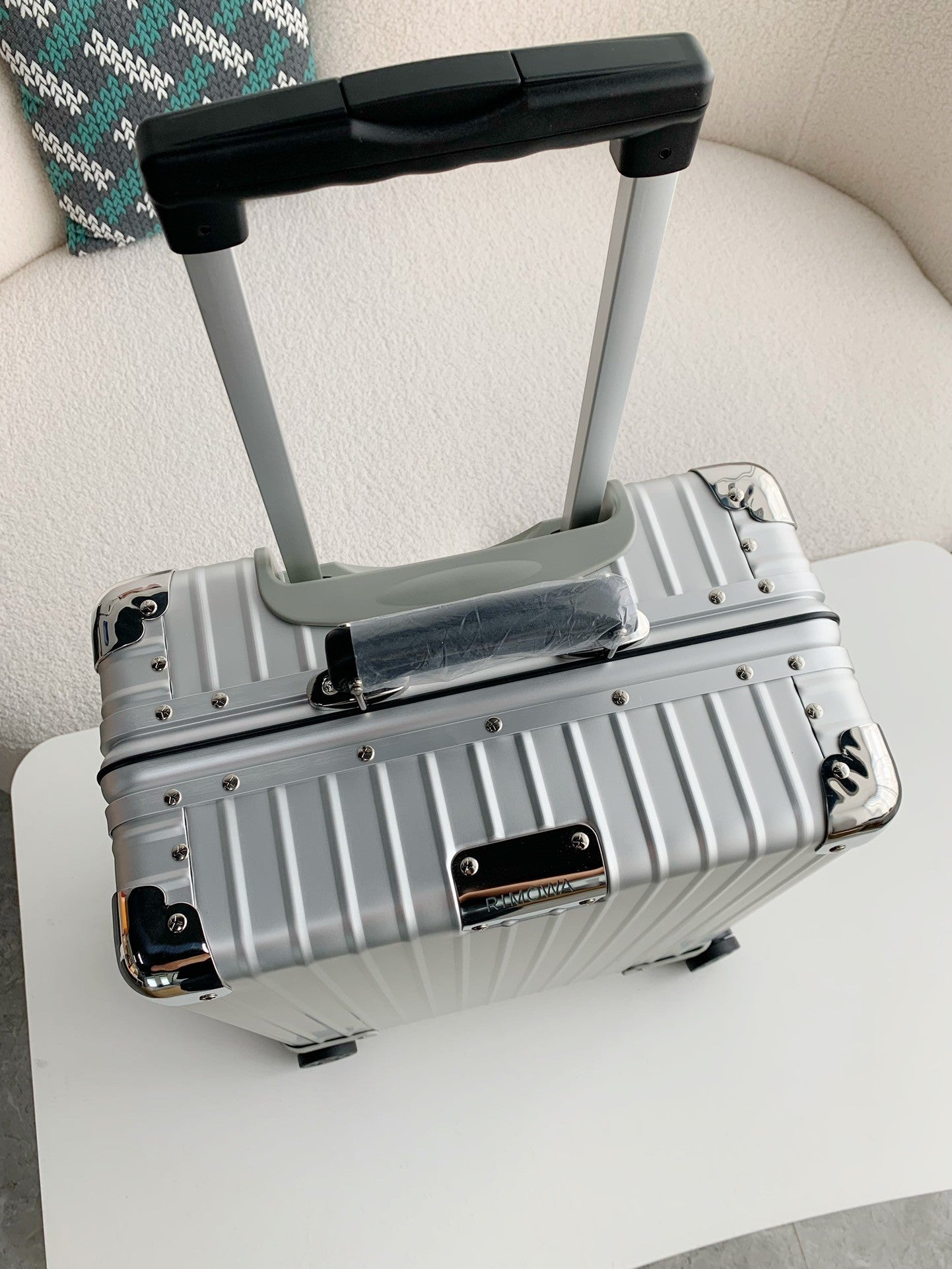 Silver suitcase with a black handle on a white surface