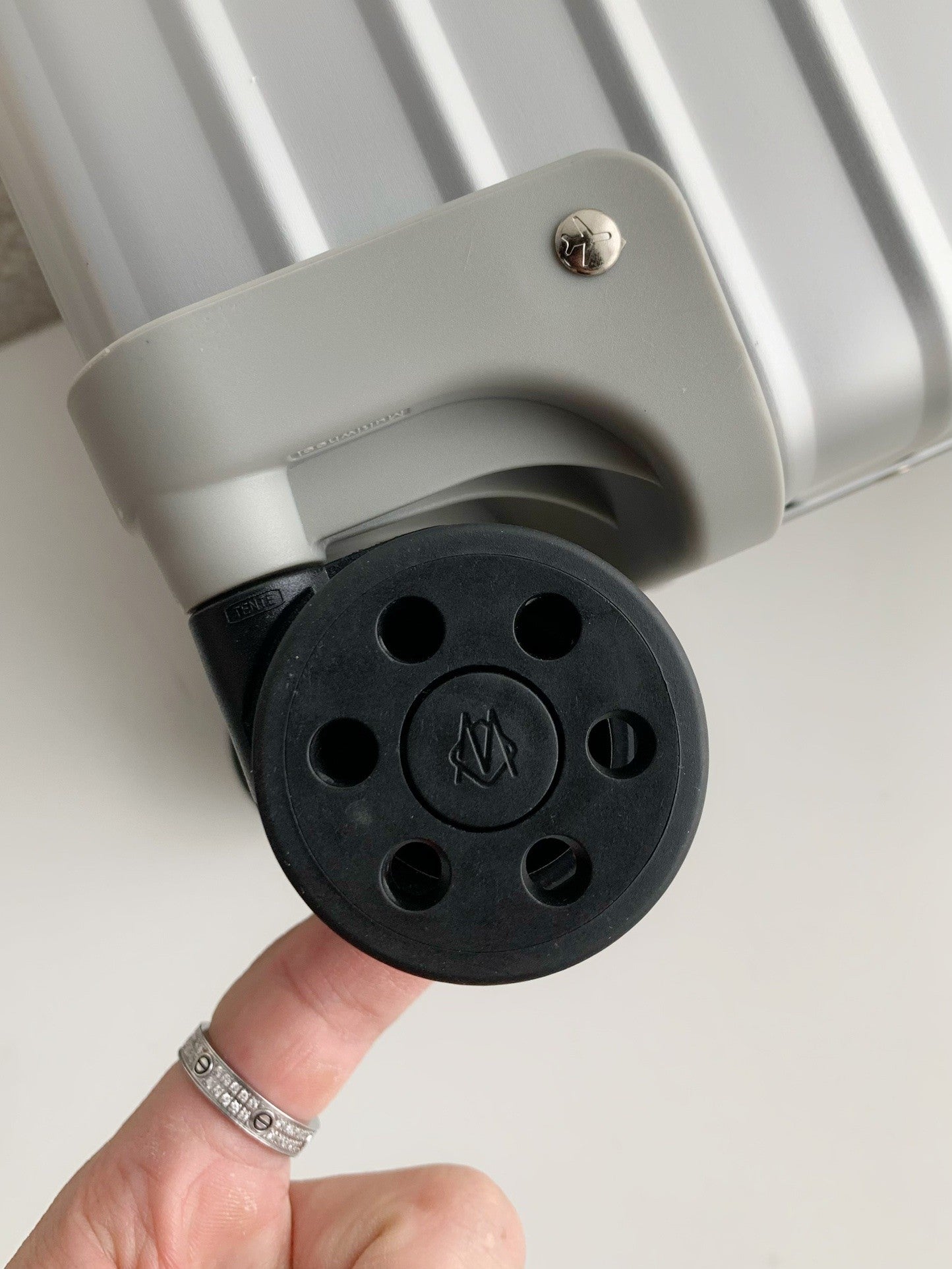 Close-up of a black electrical plug being held by a hand with a ring on a light background