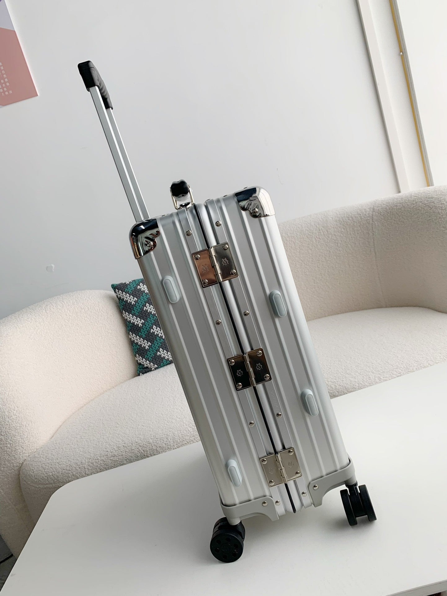 Silver suitcase on a white surface with a light gray background