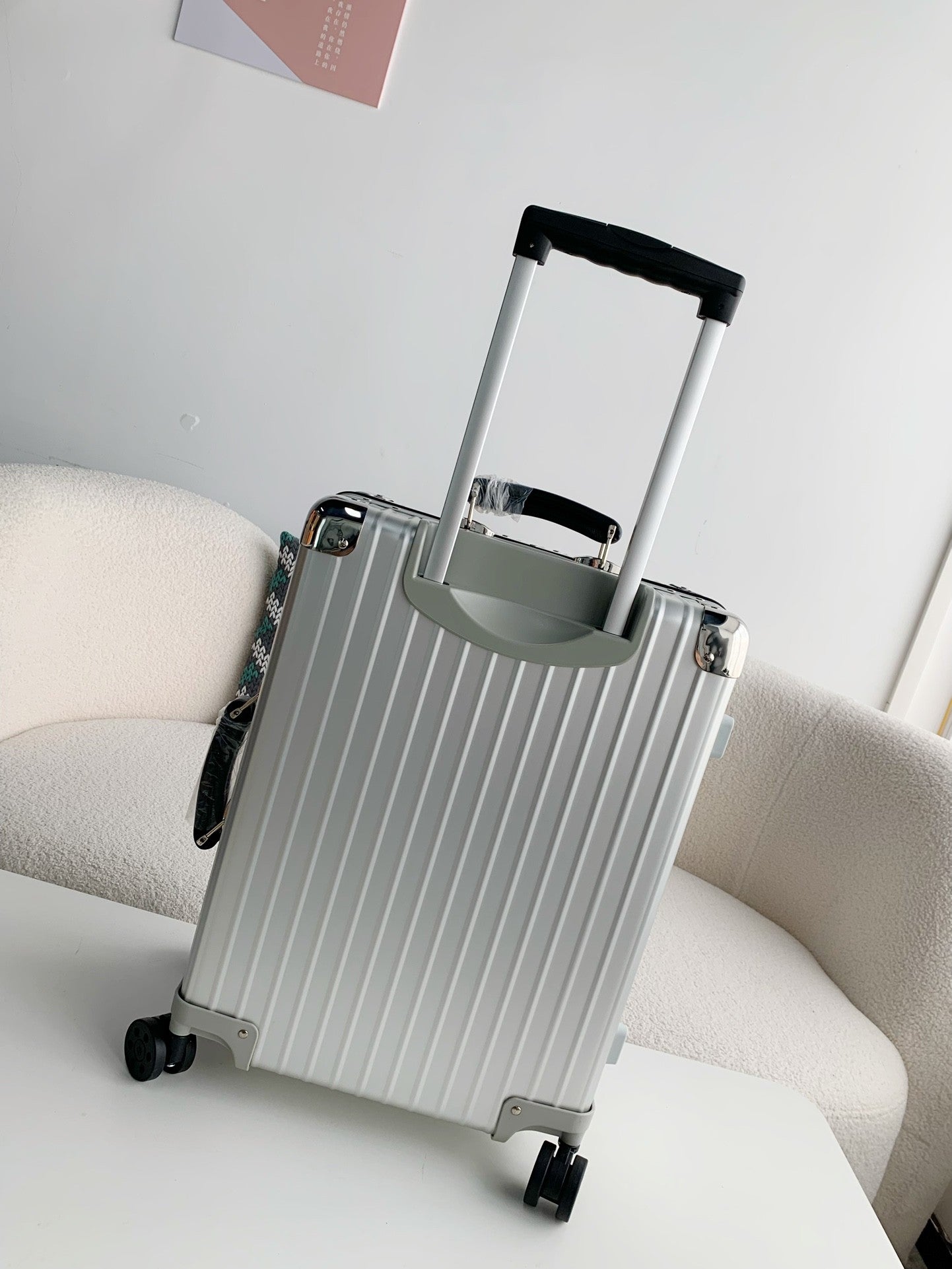 Silver suitcase with a handle on a white surface