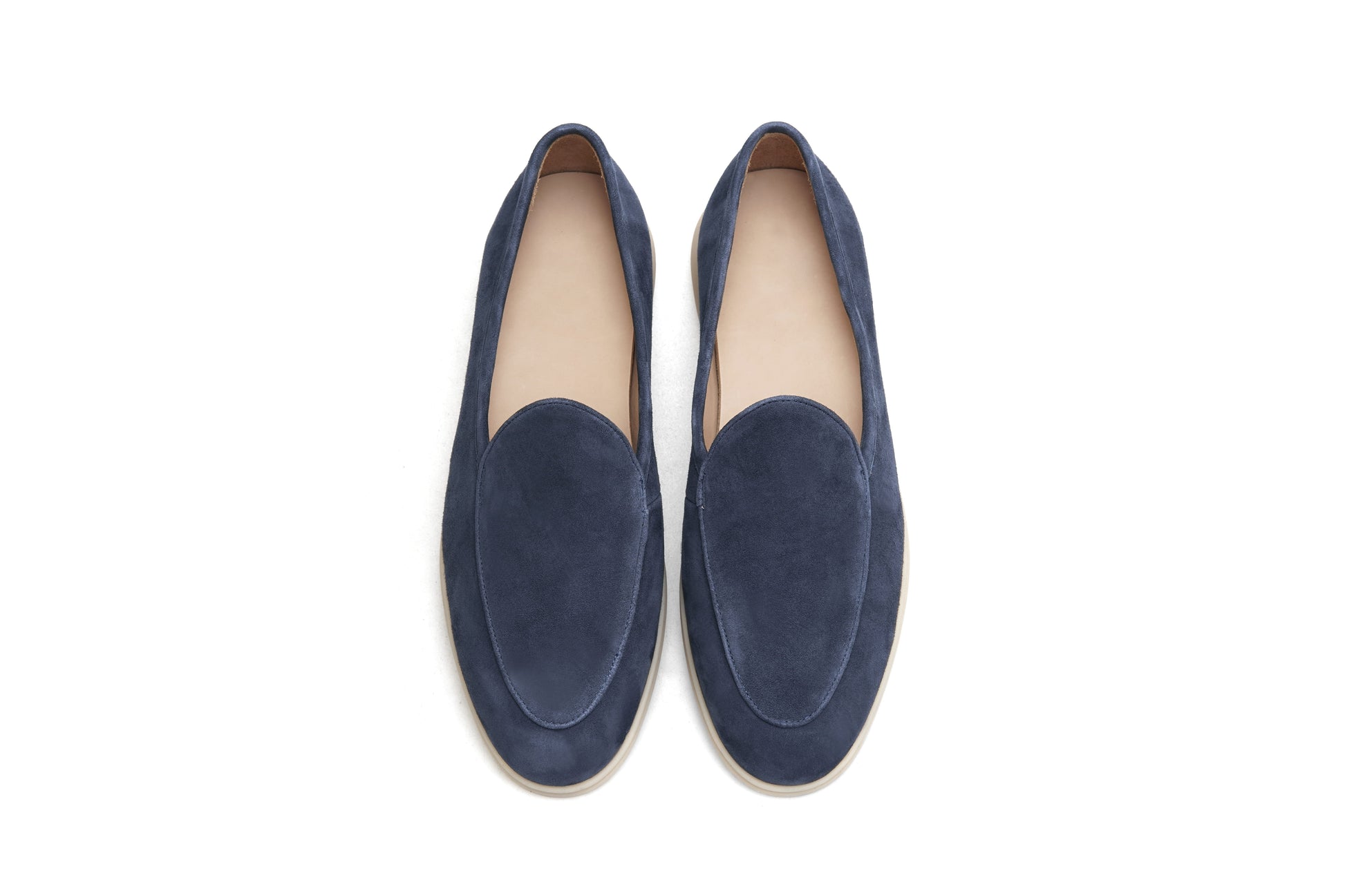 Pair of navy blue suede Venetian loafers on white background, heel and sole view