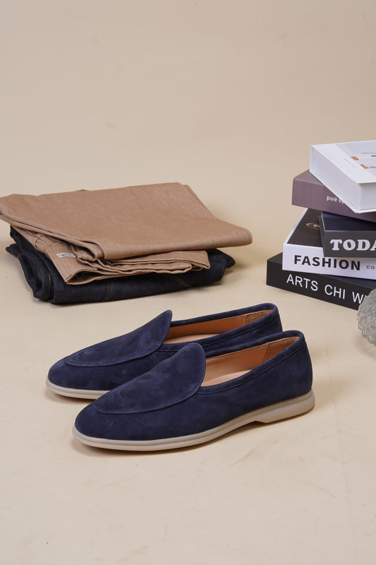 Portofino navy blue suede Venetian loafers with folded clothes and books, angled pair
