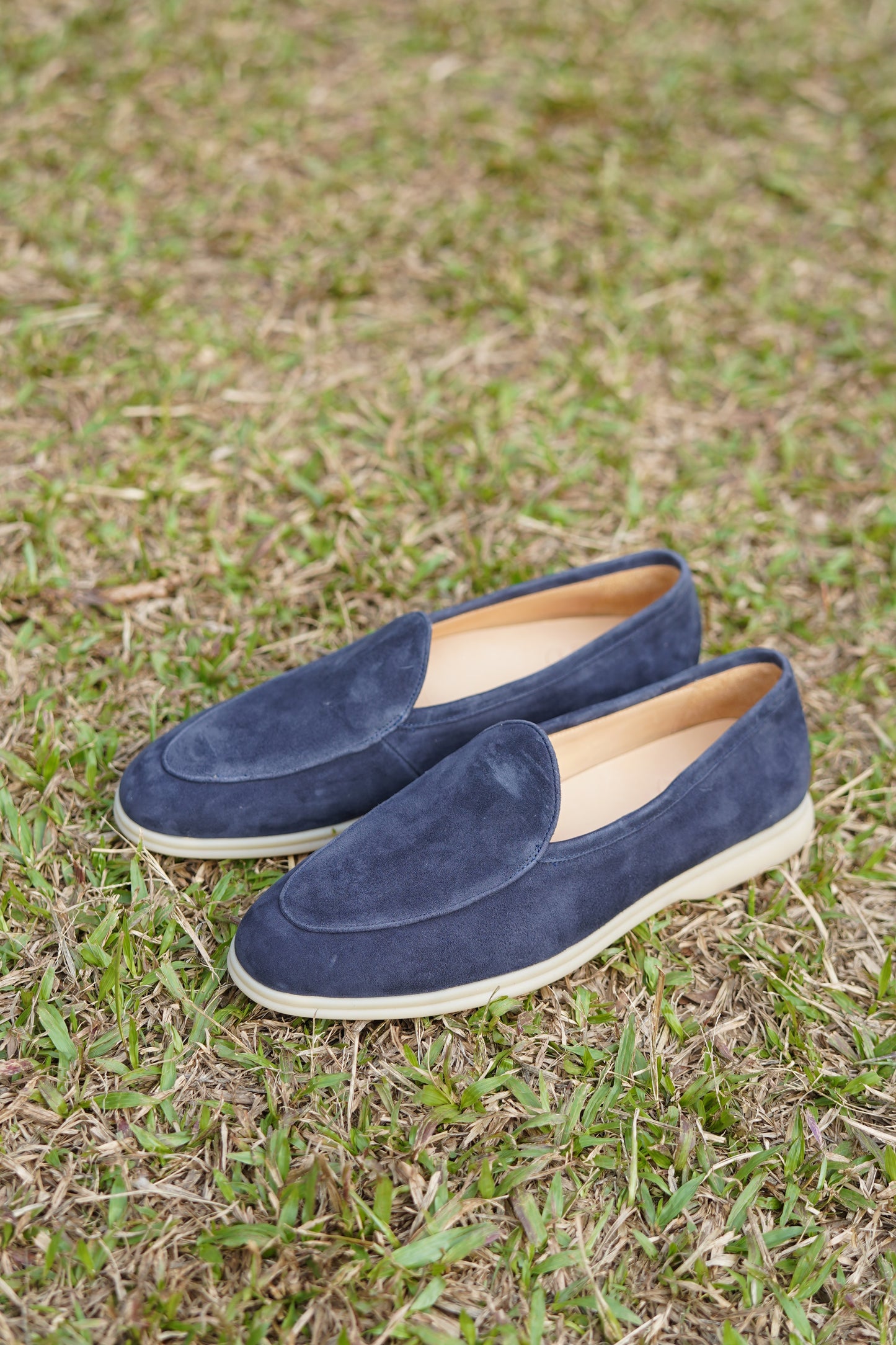Pair of Portofino navy blue suede Venetian loafers on grass, outdoor view