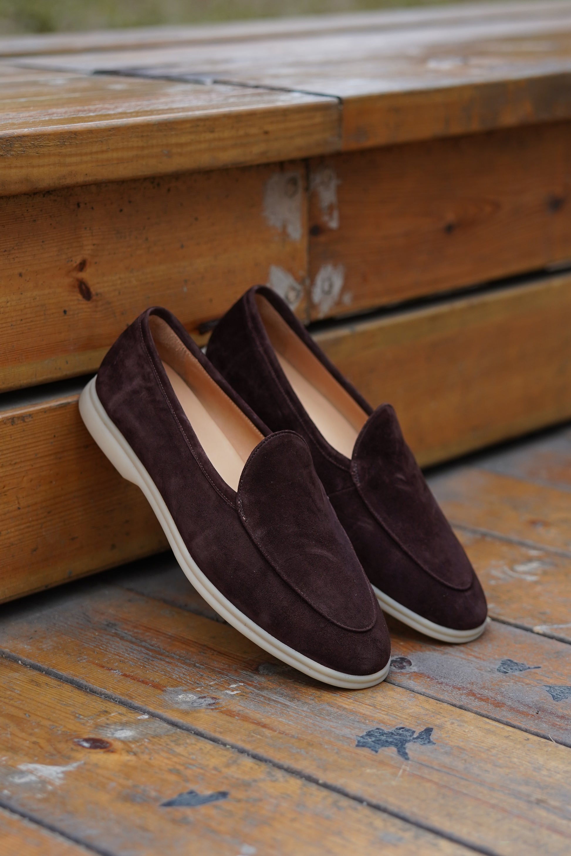 Coffee-brown suede Venetian loafers on a wooden surface, angled view