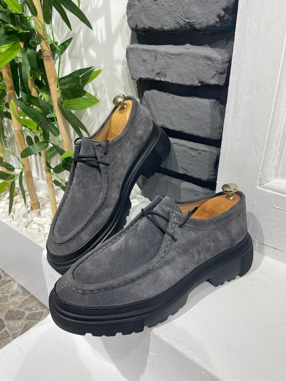 Stylish Grey Suede Lace-Up Chunky Shoes – urban footwear on a white ledge against a brick wall, with lace-up closure for secure fit.