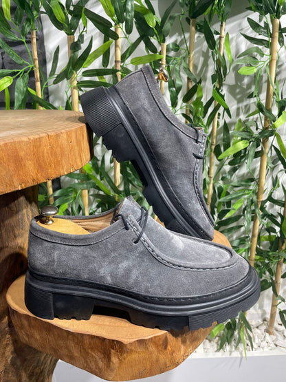Rugged Grey Suede Lace-Up Shoes – luxurious suede upper, displayed on wooden surface with green plants, offering bold design and comfort.