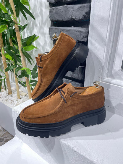 Rugged Tan Suede Lace-Up Shoes – luxurious suede upper, displayed on a white ledge with a brick wall, offering bold design and comfort.