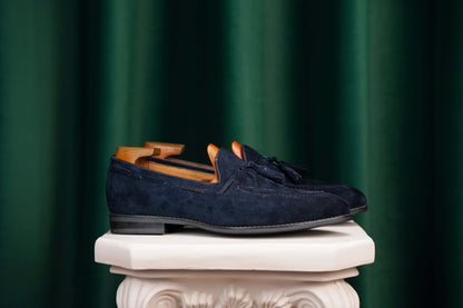 Handcrafted Sapphire Navy Tassel Suede Loafers – pair with shoe trees, resting on a white classical pedestal, highlighting rich navy suede.