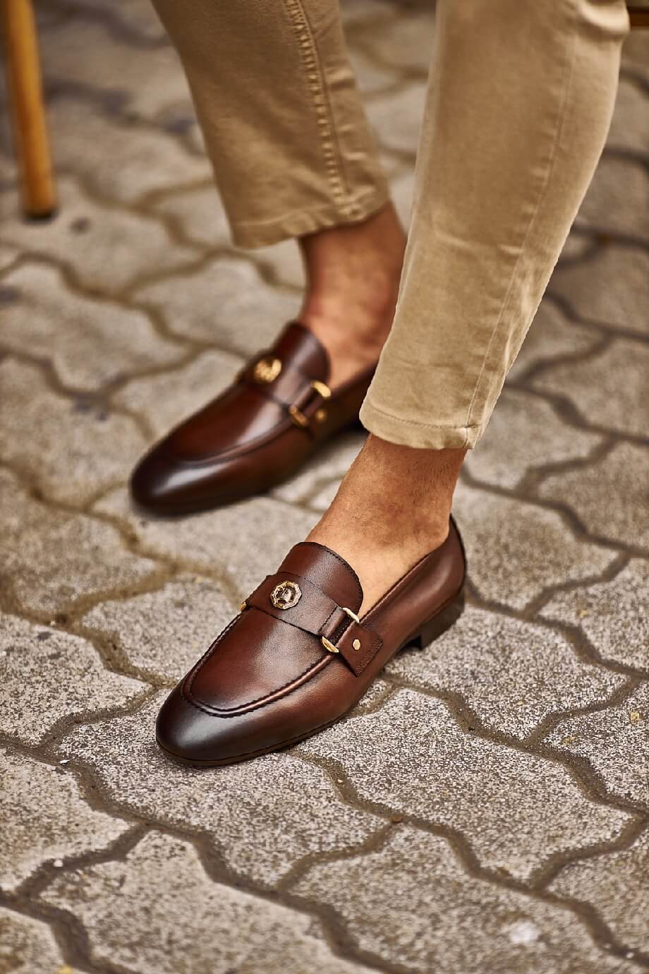 Sophisticated Brown Leather Penny Loafers for Business & Casual Wear – worn by a man in tan chinos, with one foot on a wooden step, showcasing the elegant horsebit detail and versatile style.