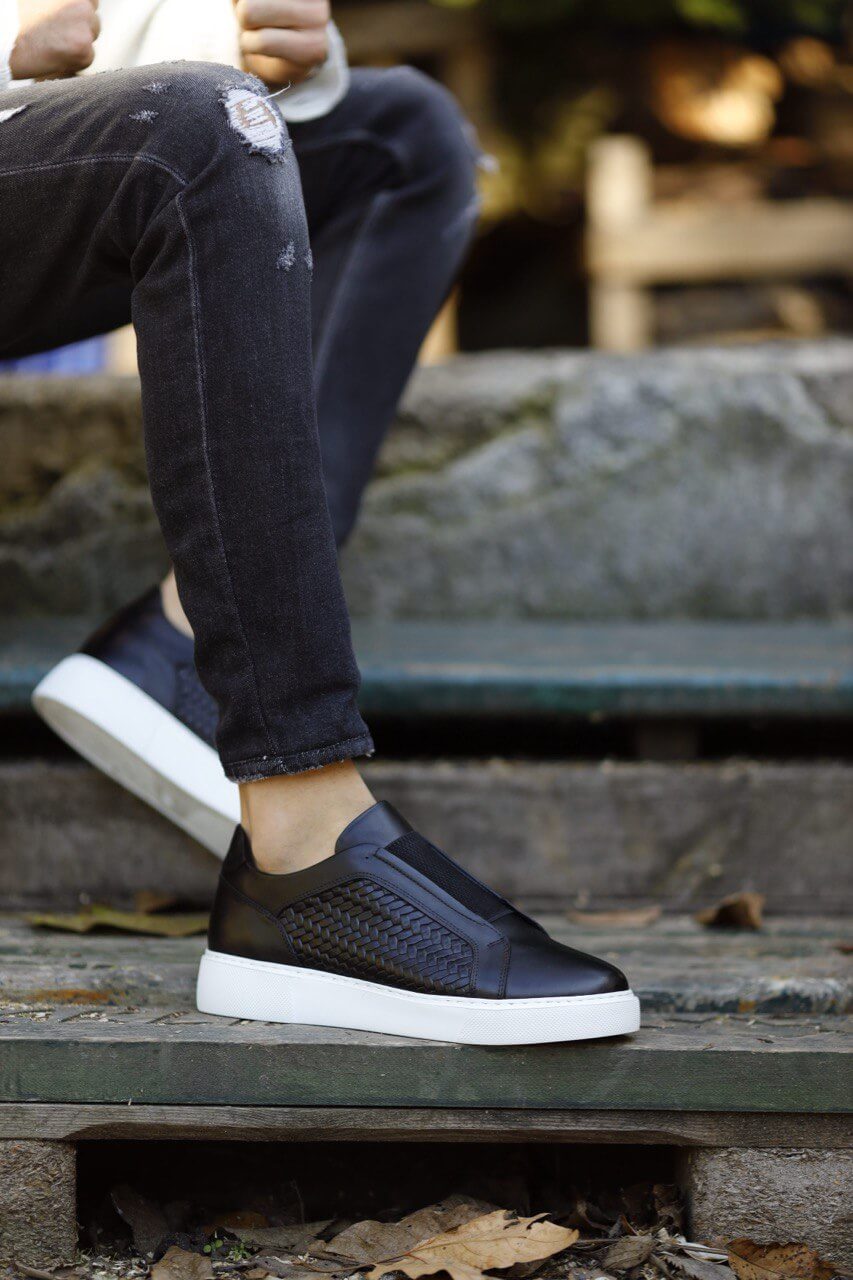 Special Design Black Straw Detail Leather Sneakers – worn by a man in distressed black jeans, sitting on a step, highlighting a unique straw detail and sleek design.