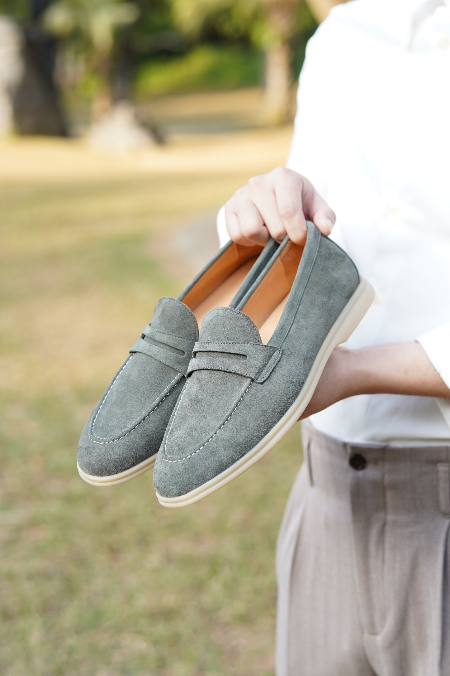 Man wearing pale cyan suede penny loafers outdoors, on-foot view