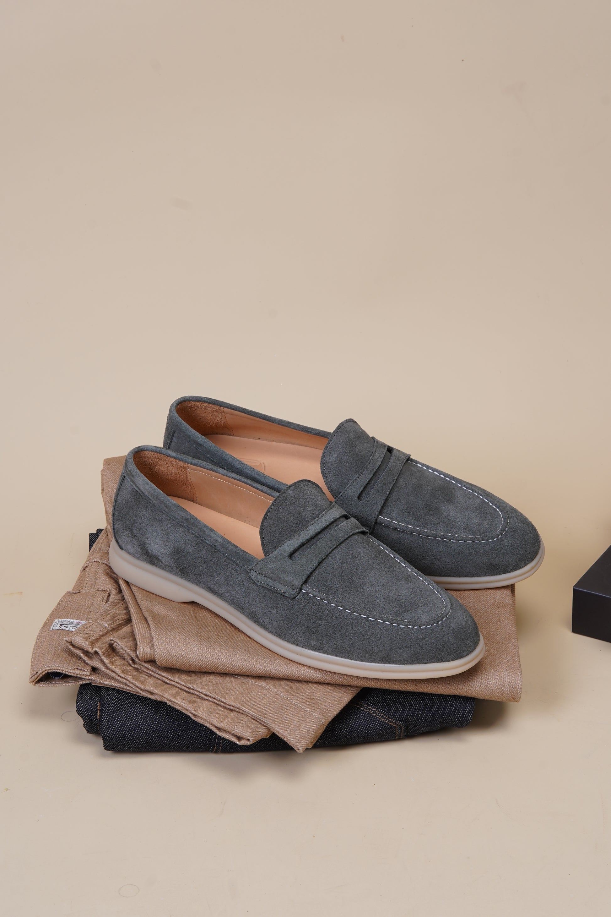 Pair of pale cyan suede penny loafers on beige background, top view