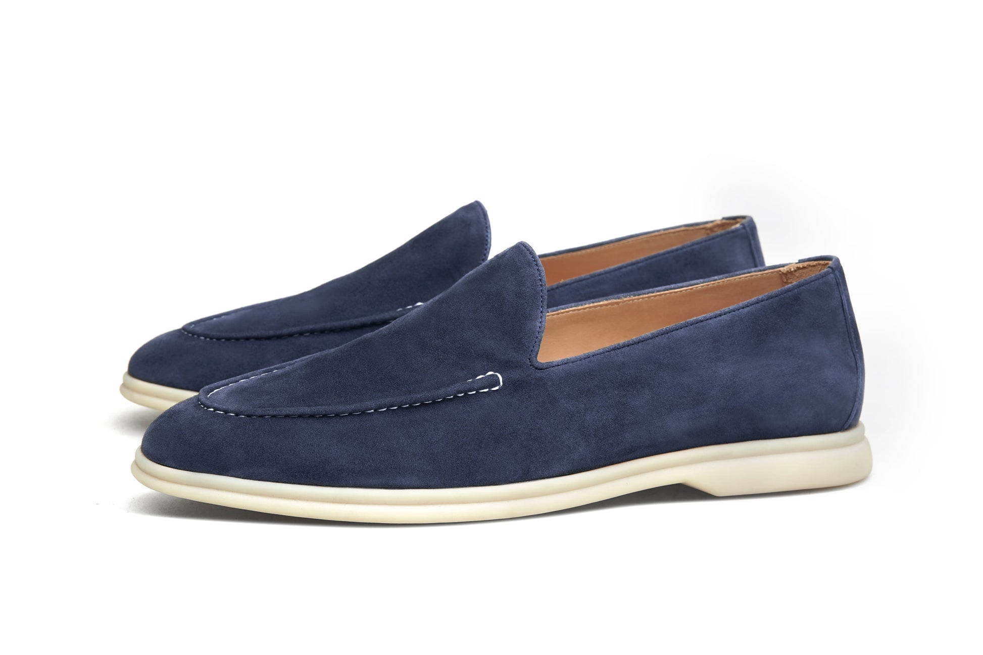 Pair of deep navy suede penny loafers on white background, front view