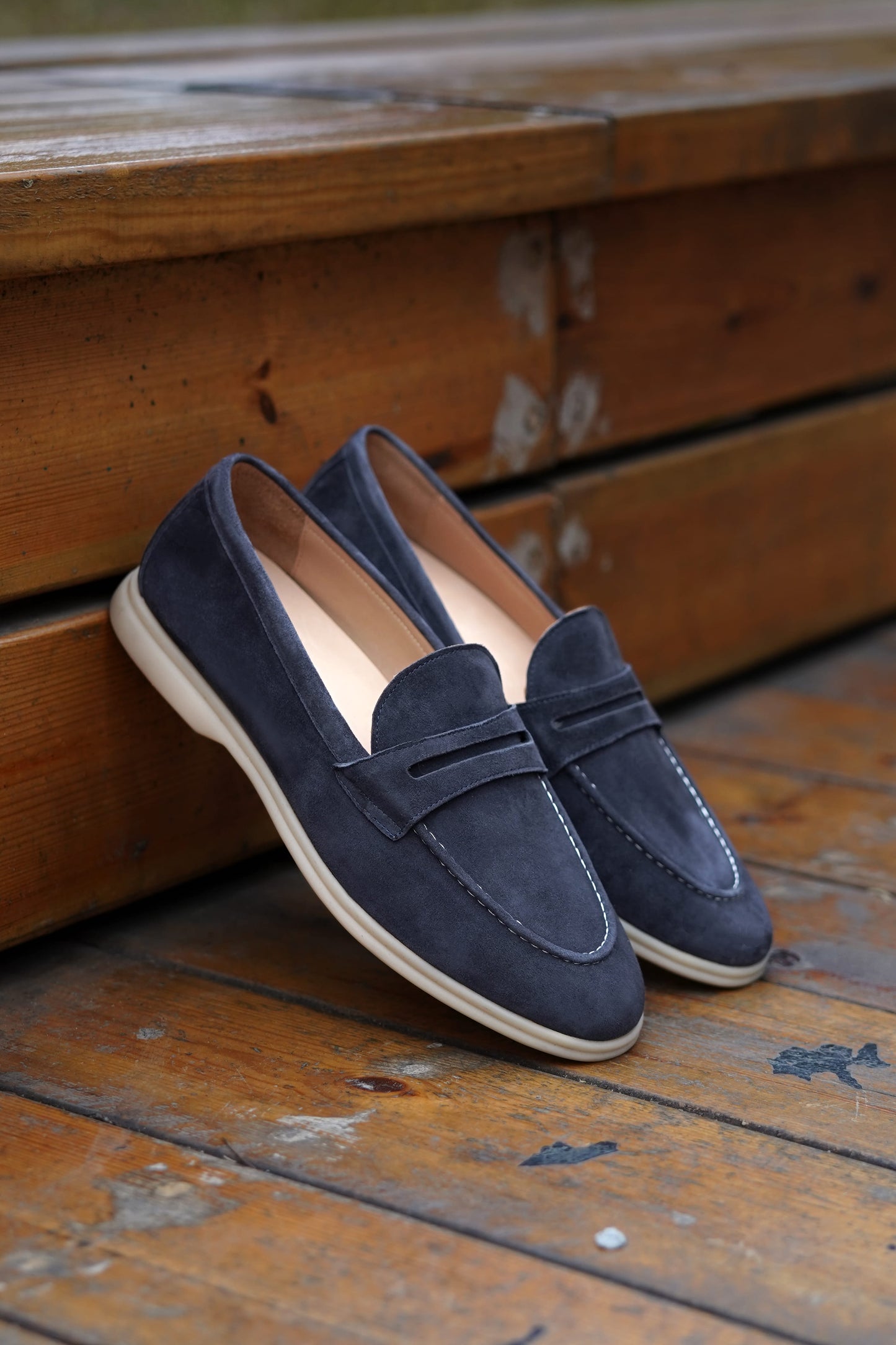 Navy blue suede penny loafers on beige background, top view