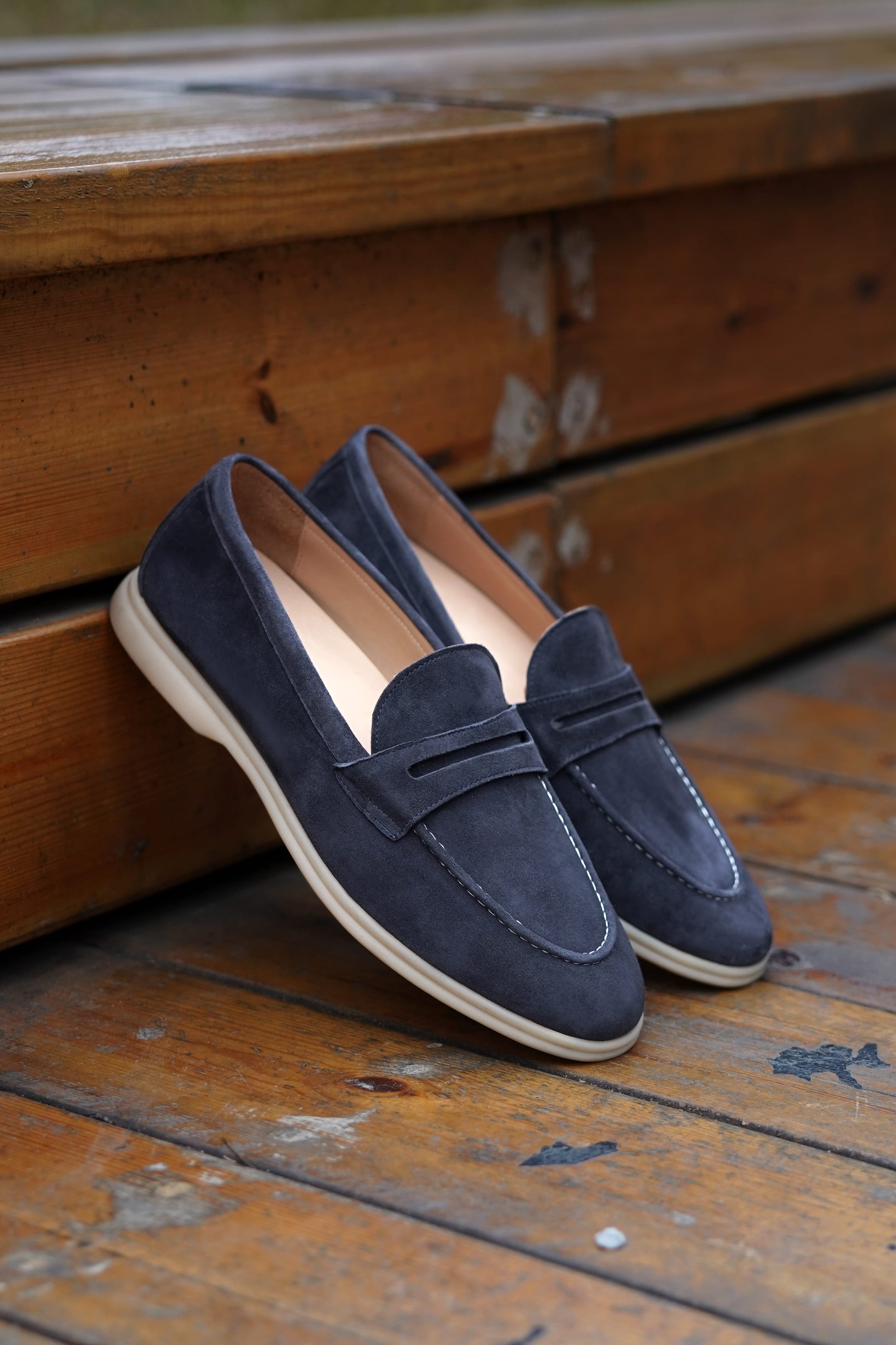 Navy blue suede penny loafers on beige background, top view