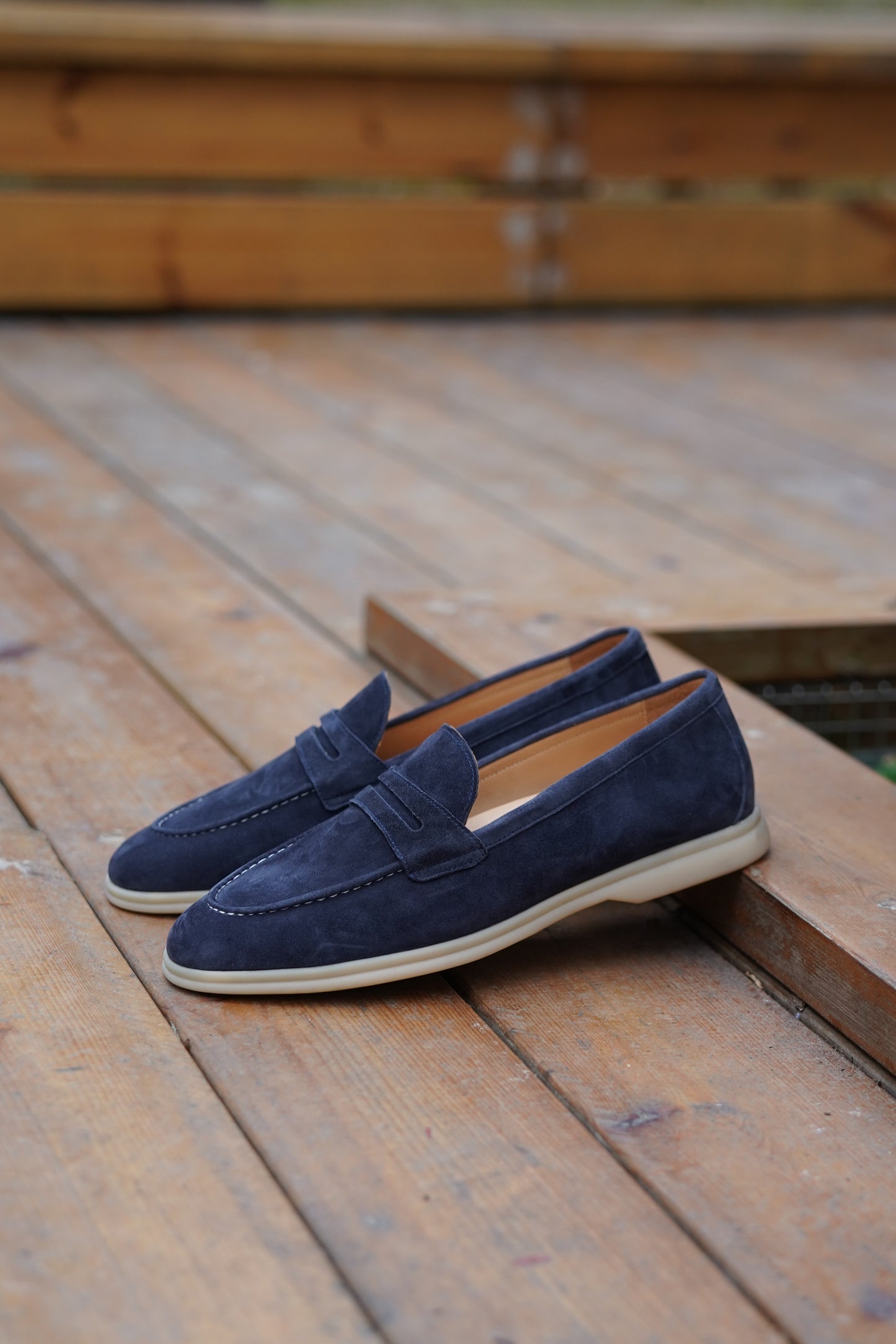 Navy blue suede penny loafers outdoors, three-quarter view
