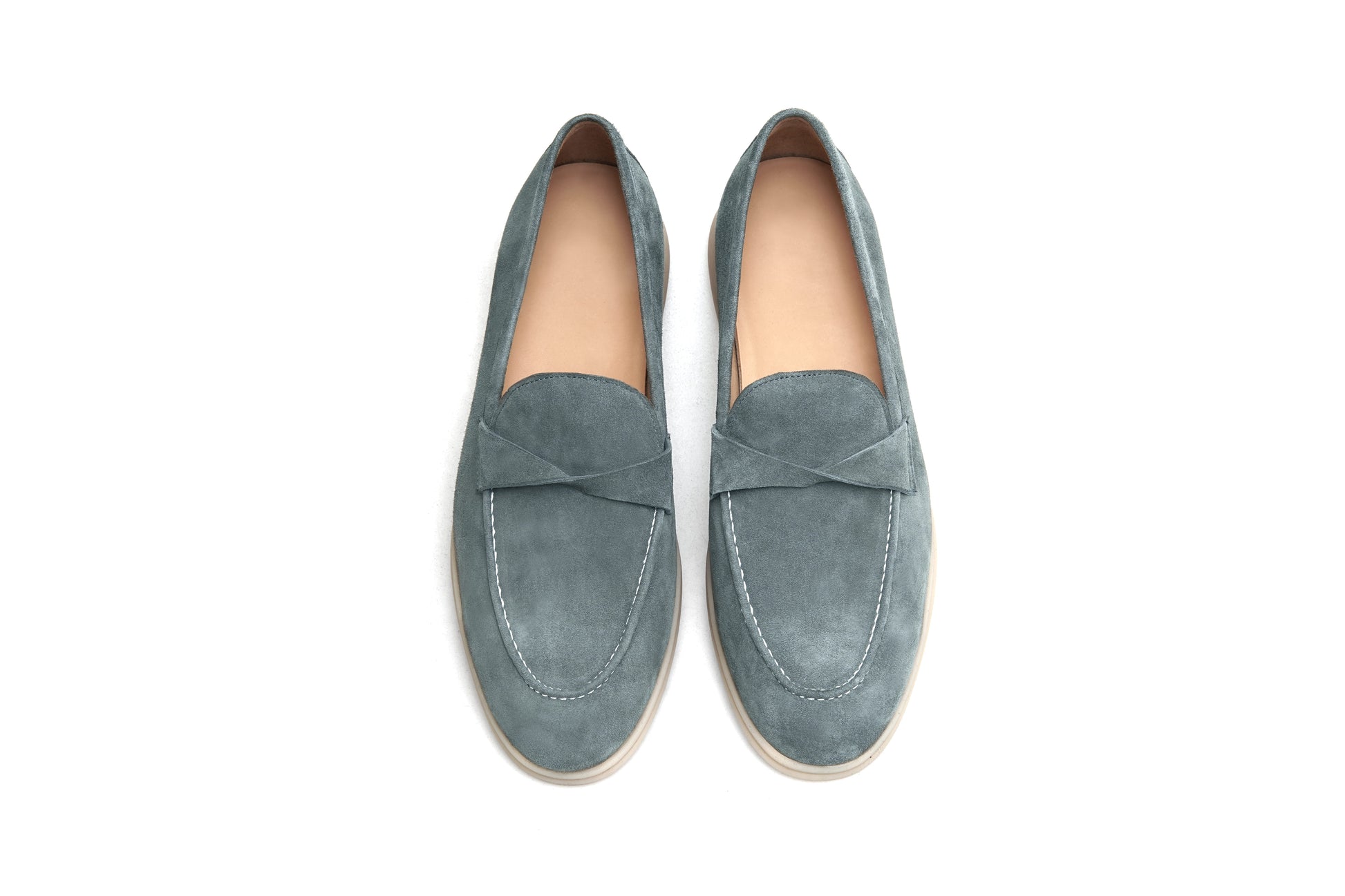 Pair of green suede twist-strap loafers on white background, front view