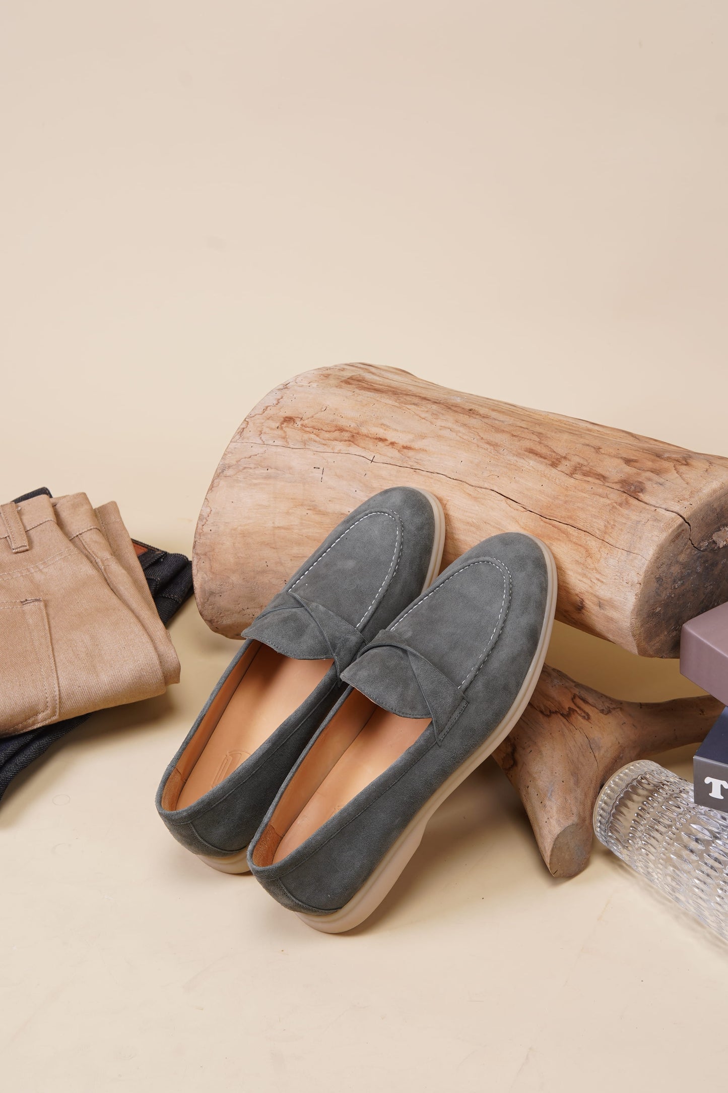 Green suede twist-strap loafers on beige background, top view