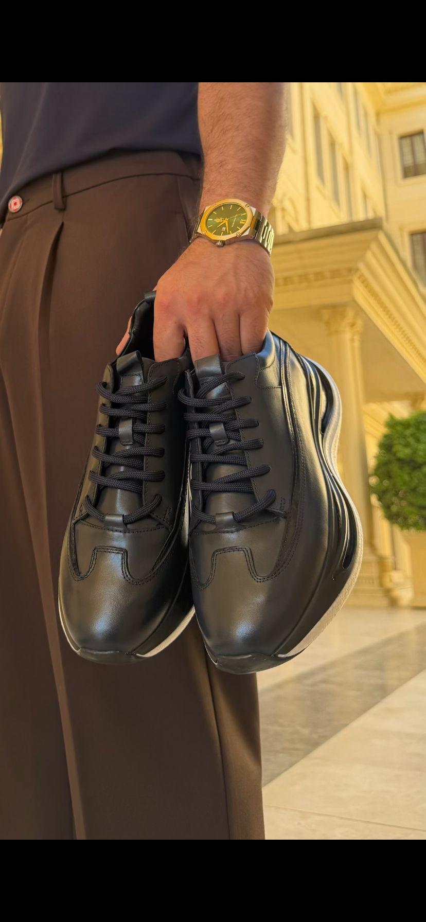 Front view of Torino black leather runner sneaker held by hand, showcasing smooth leather upper and oversized sole.