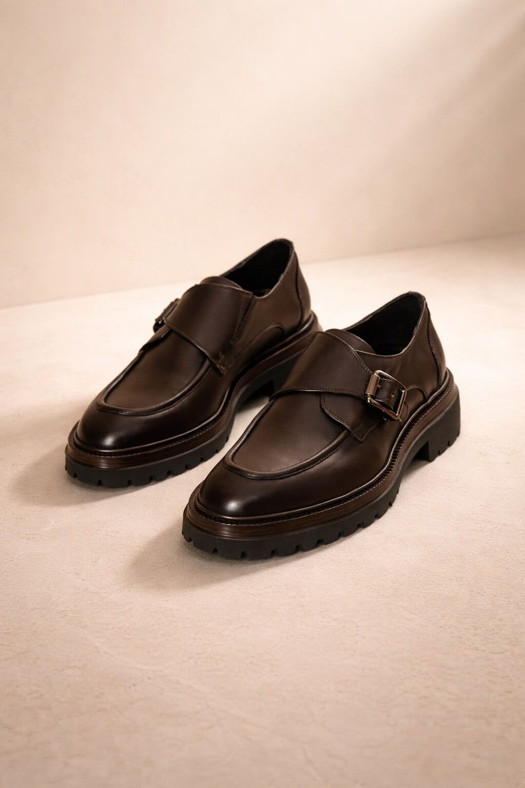 Pair of brown monk strap shoes on a beige background
