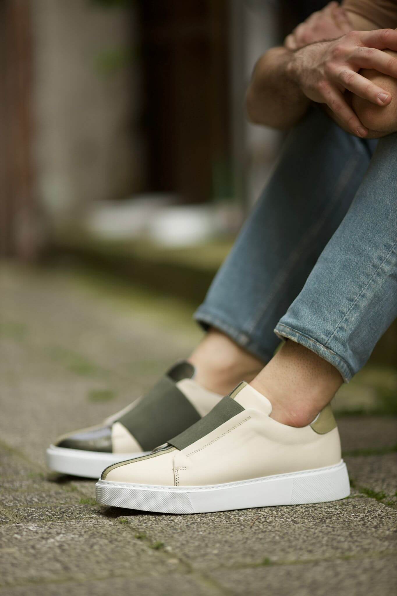 Vince Beige & Green Slip-On Sneakers - Sophisticated Comfort for Every Occasion – worn by a man in blue jeans, sitting, showcasing the two-tone leather and thick rubber sole.