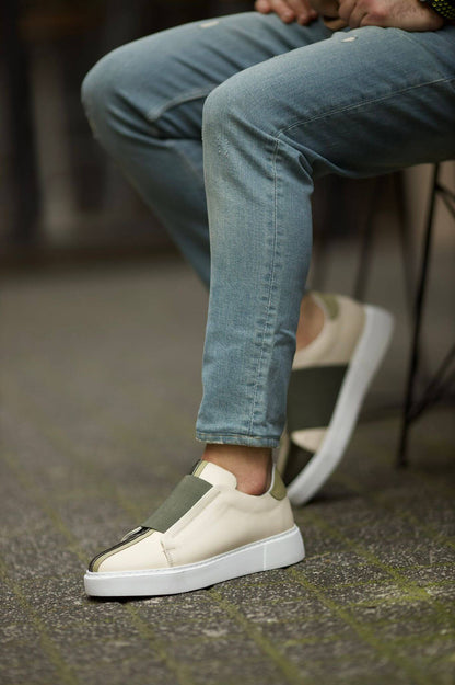Vince Beige & Green Slip-On Sneakers - Sophisticated Comfort for Every Occasion – a man sitting in blue jeans, with one foot elevated, highlighting the two-tone leather and slip-on style.