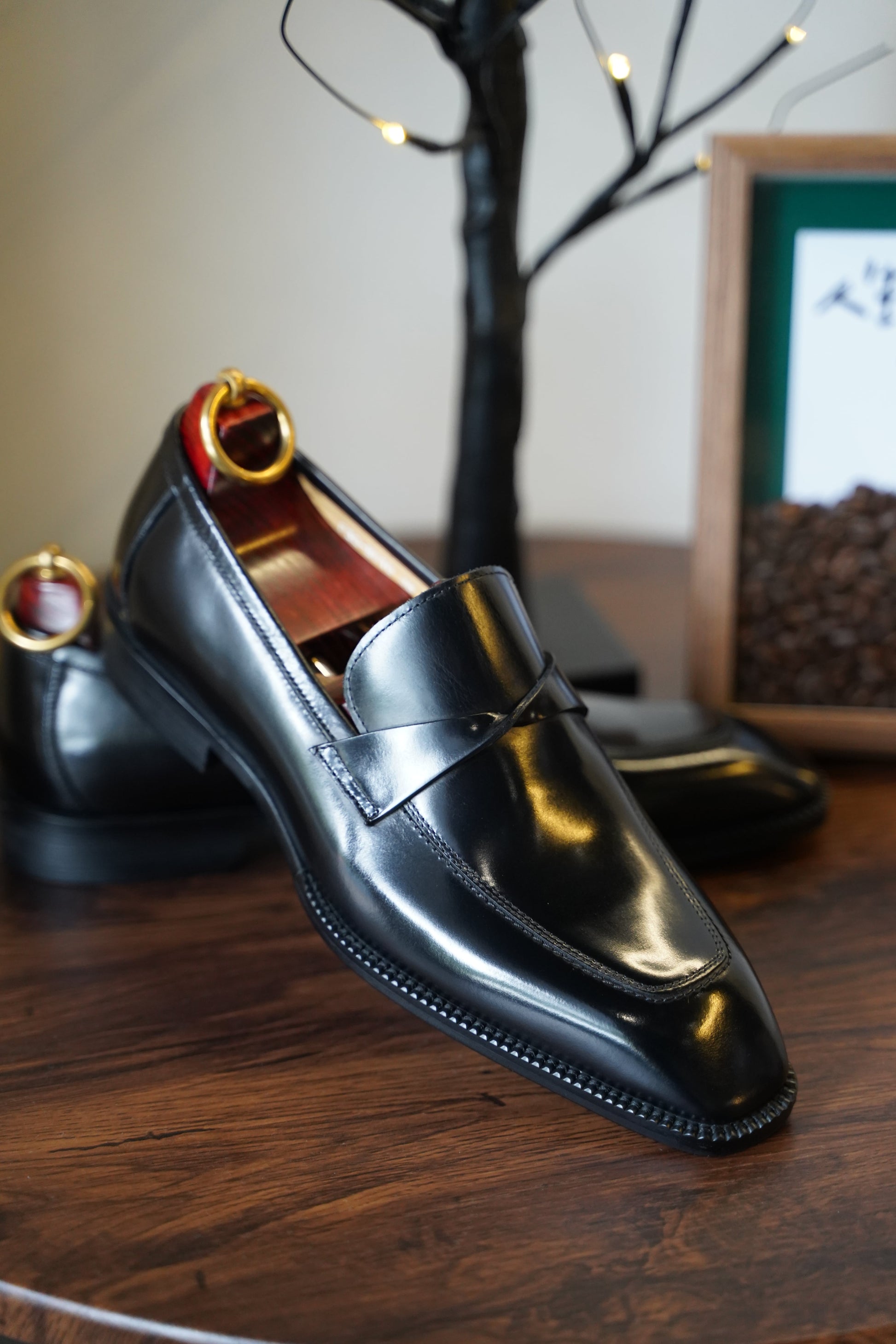 Black leather loafers with a unique knotted penny strap design, designed for comfort and style.