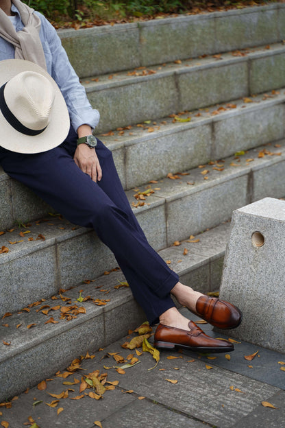 Brown Penny loafers with rolled-up navy pants.