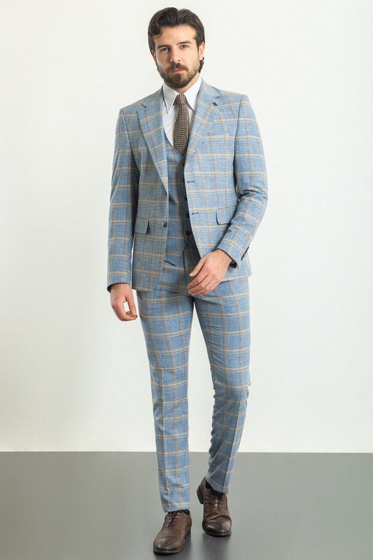 A stylish man wearing a Blue Checkered Three-Piece Suit stands confidently in a studio setting. The suit features a light blue color with a yellow checkered pattern, paired with a white dress shirt and a brown patterned tie, adding a touch of contrast and sophistication. Brown leather dress shoes complete the ensemble, enhancing the outfit's classic and elegant look. The man has neatly groomed hair and a trimmed beard, exuding a polished and refined appearance ideal for formal occasions.