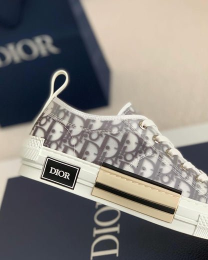 A pair of white Dior B23 High-Top sneakers with a transparent panel showcasing the Dior Oblique jacquard canvas.