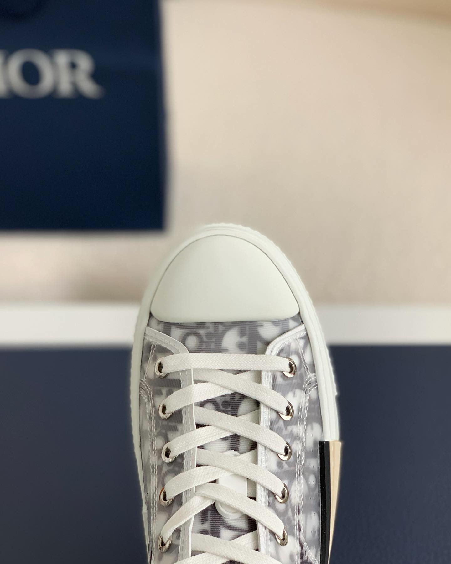 A pair of white Dior B23 High-Top sneakers with a transparent panel showcasing the Dior Oblique jacquard canvas.