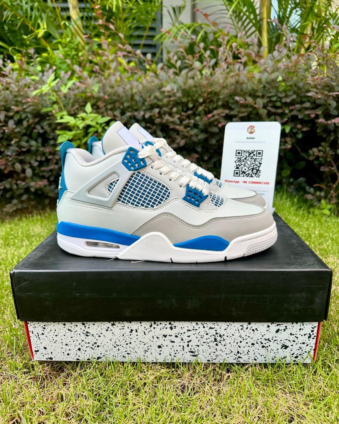 A pair of white Air Jordan 4 sneakers with Military Blue and neutral grey accents.